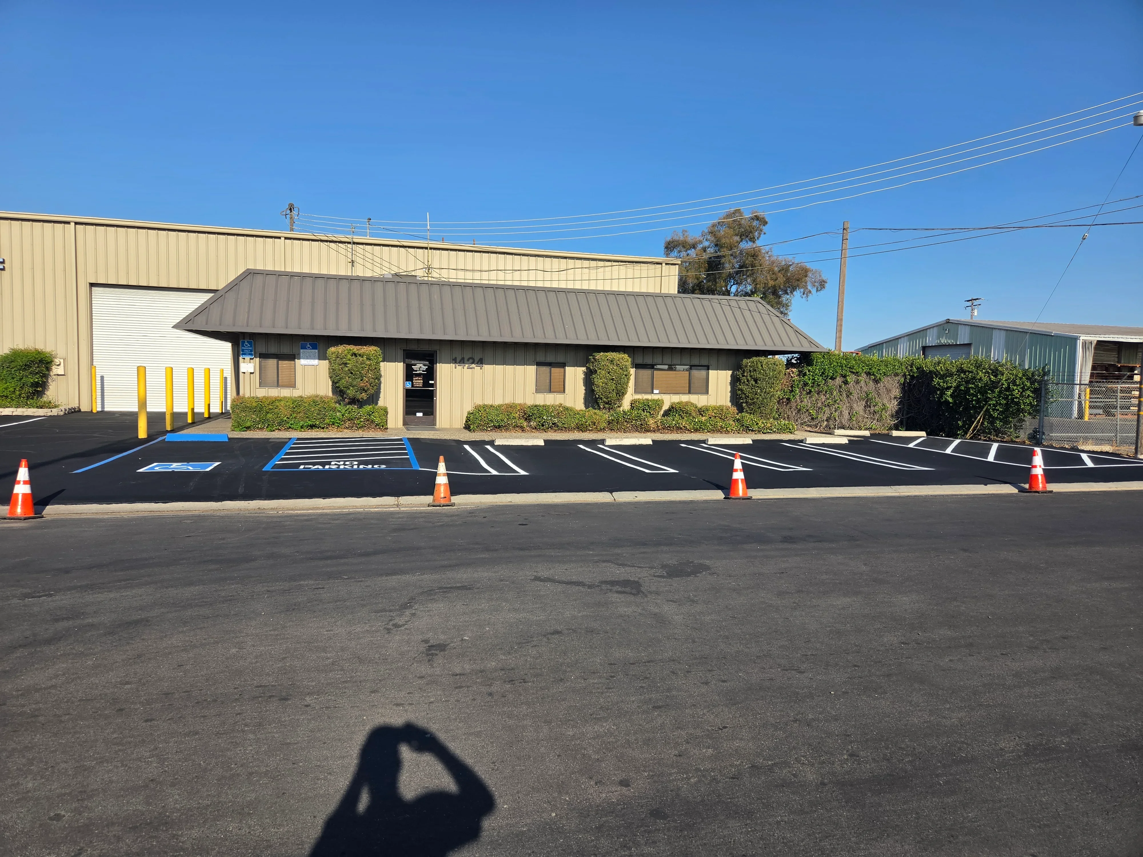 Newly sealed asphalt parking lot with white striping, blue handicap spaces, and directional markings