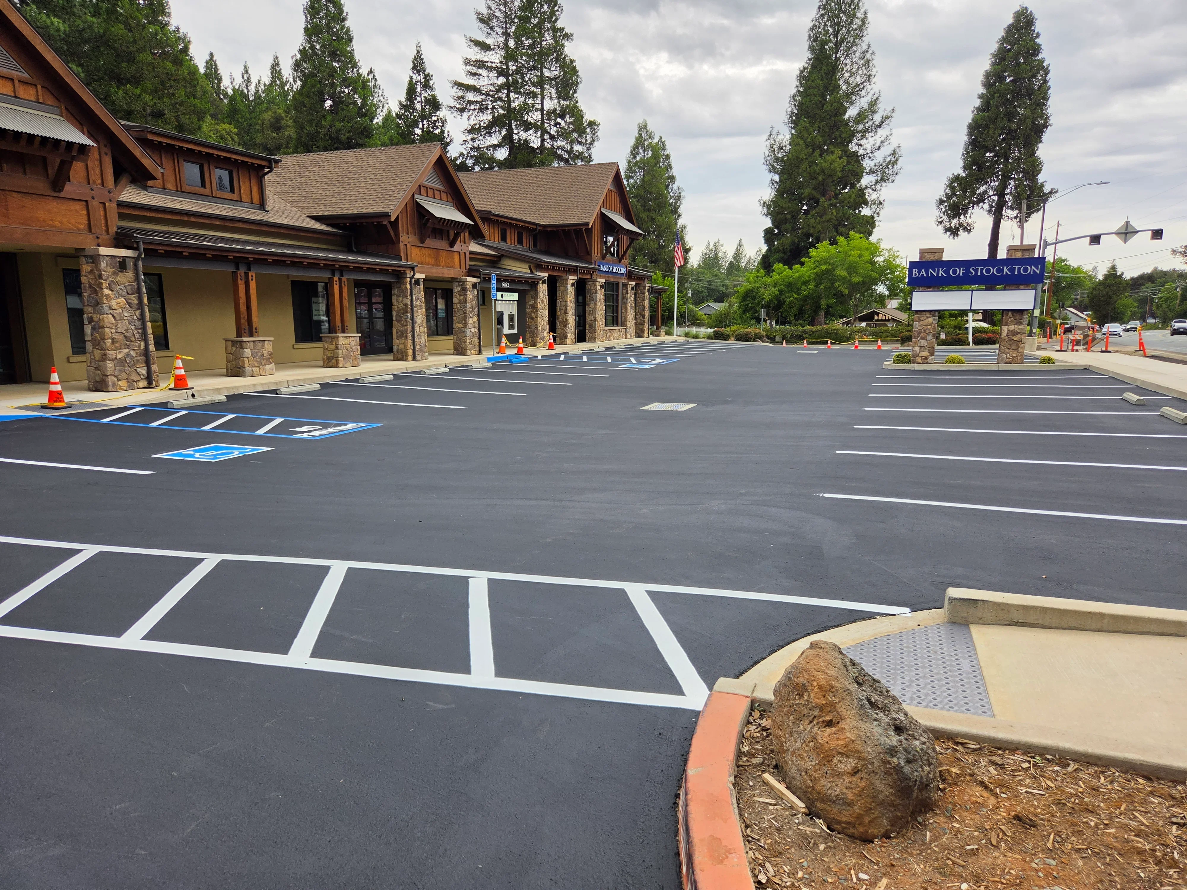 Newly paved asphalt parking lot with white striping and blue handicap spaces in front of commercial building