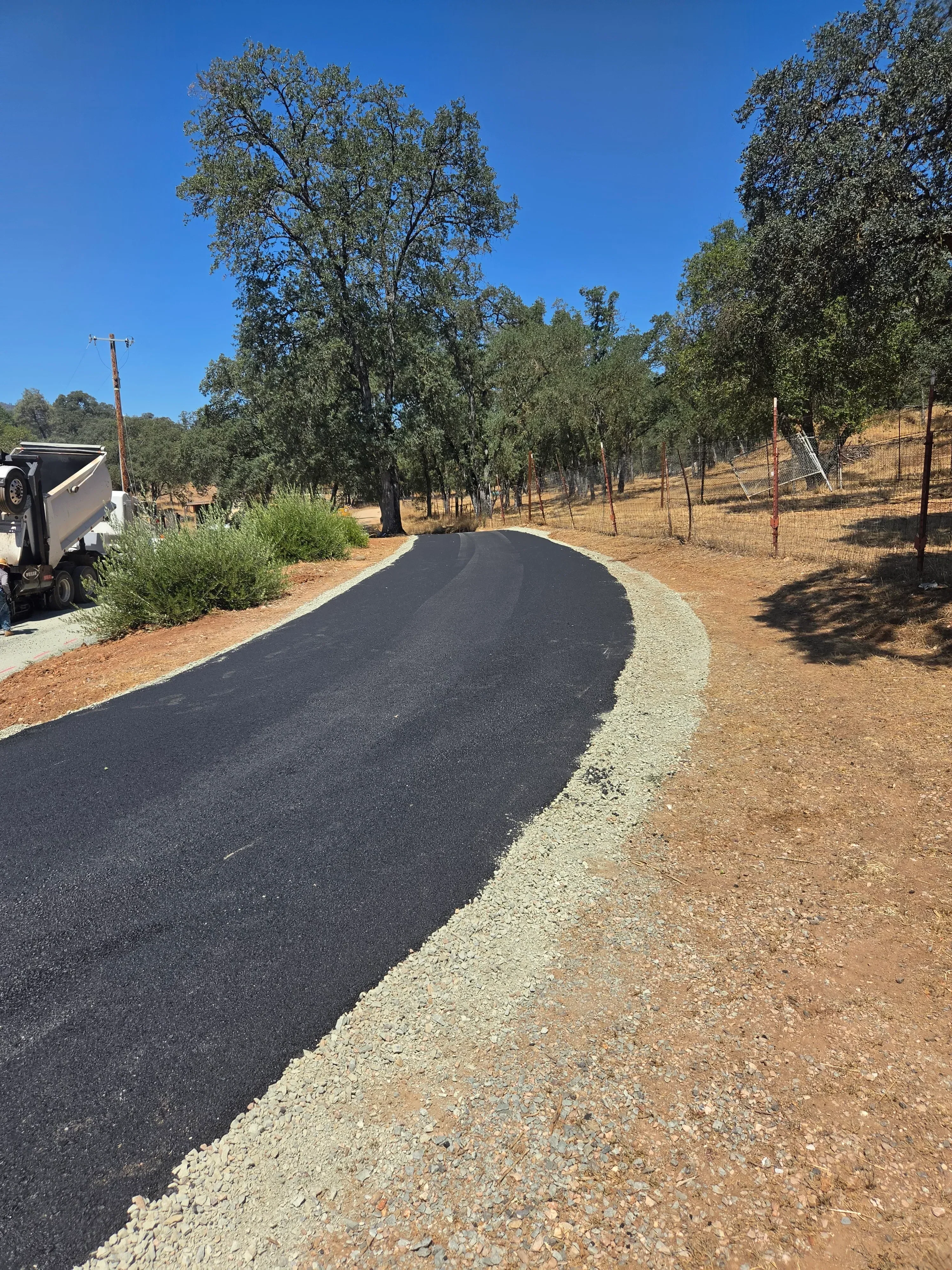 Newly paved asphalt driveway with gravel base layer and edge definition